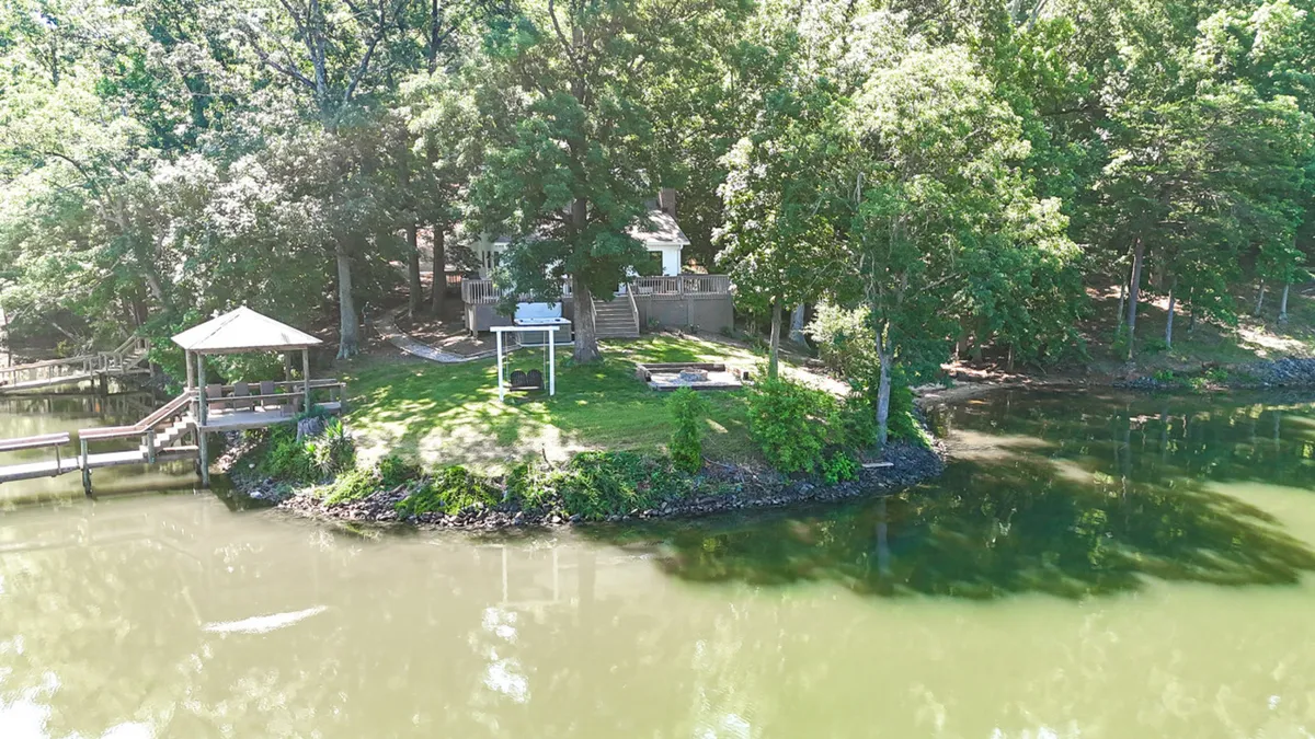 This image offers a broad view of the dock, gazebo, fire pit, and green lawn, all beside tranquil water. It’s a lively space designed for boating, fishing, picnicking, and sharing meals in the open air.